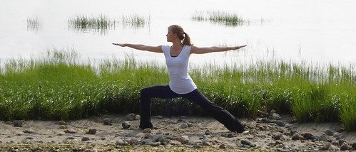 Solo practitioner in warrior II pose beside a marsh at golden hour