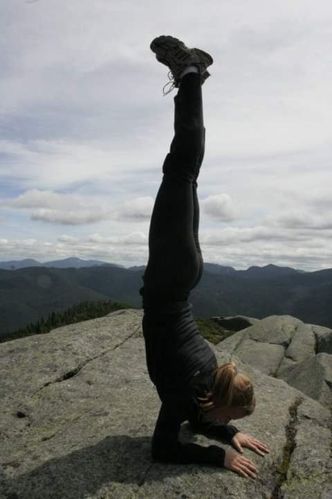 Becky Bell in a forearm balance on a mountain summit